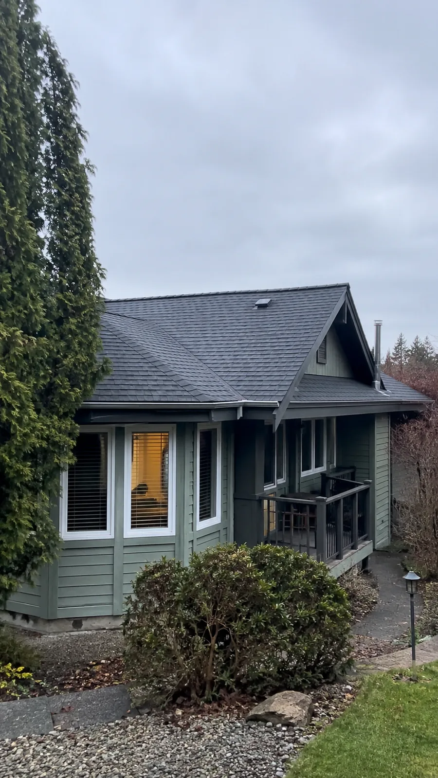 Clean dark roof on a green home with porch windows
